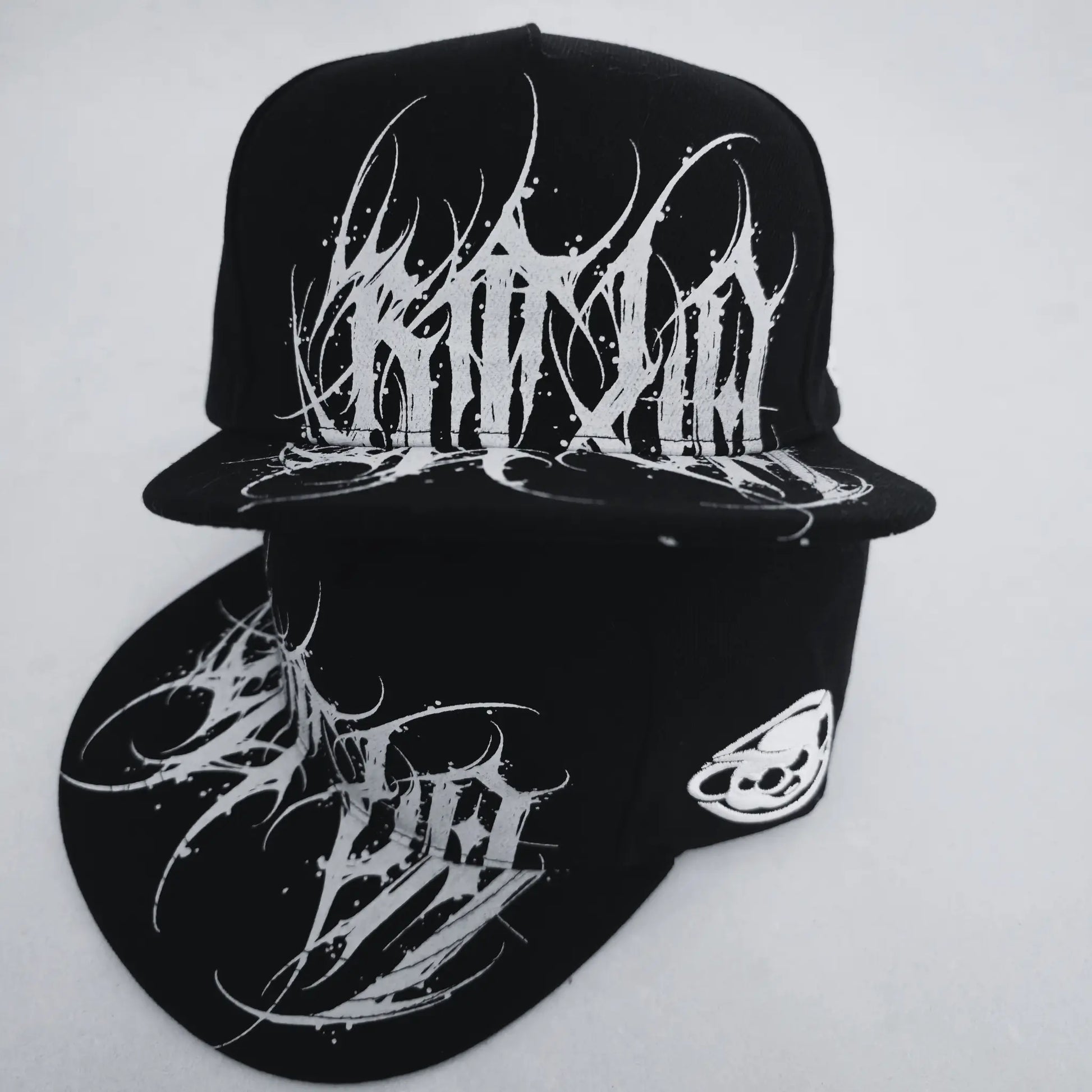 Black cap with white abstract designs on a light gray background