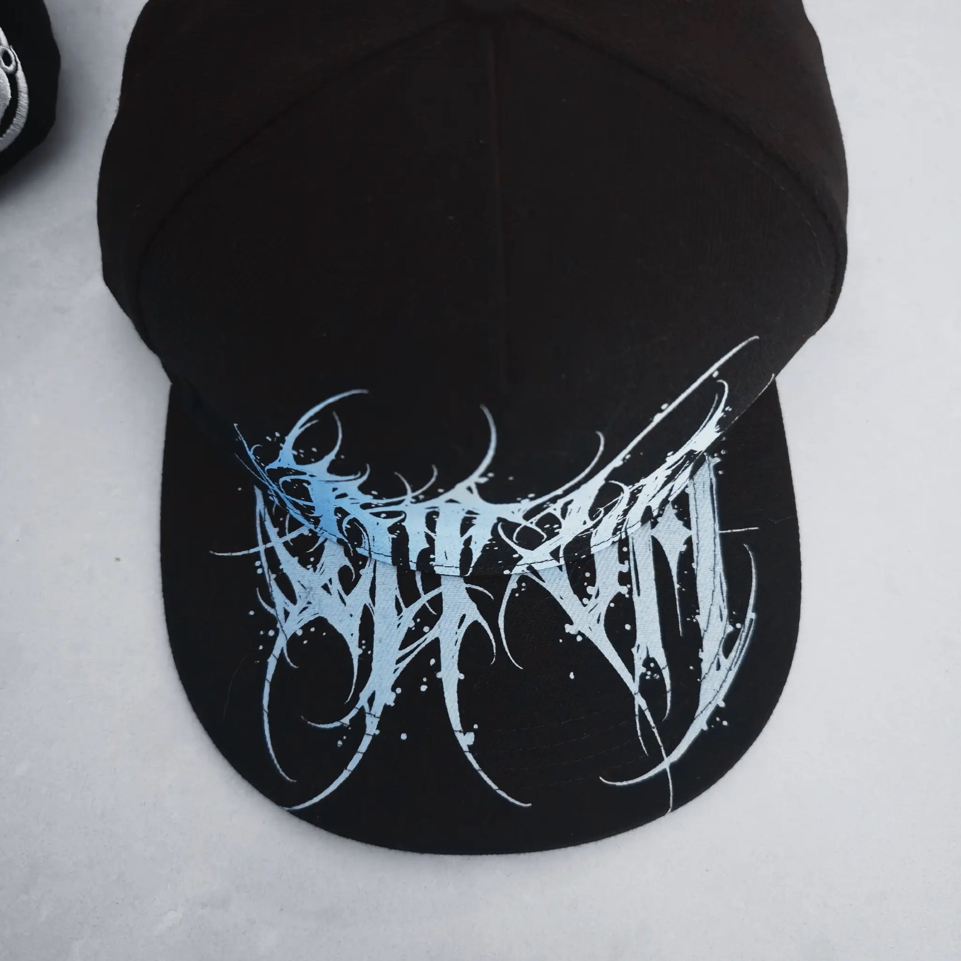 Black cap with blue and white logo on a light gray background