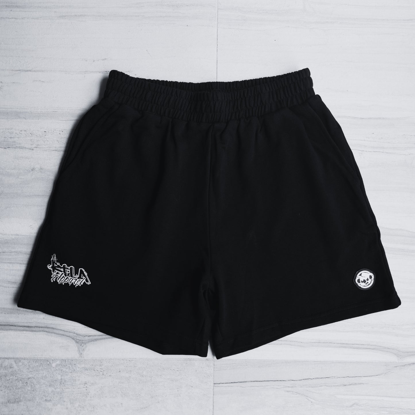Black shorts with white logos on a light gray background