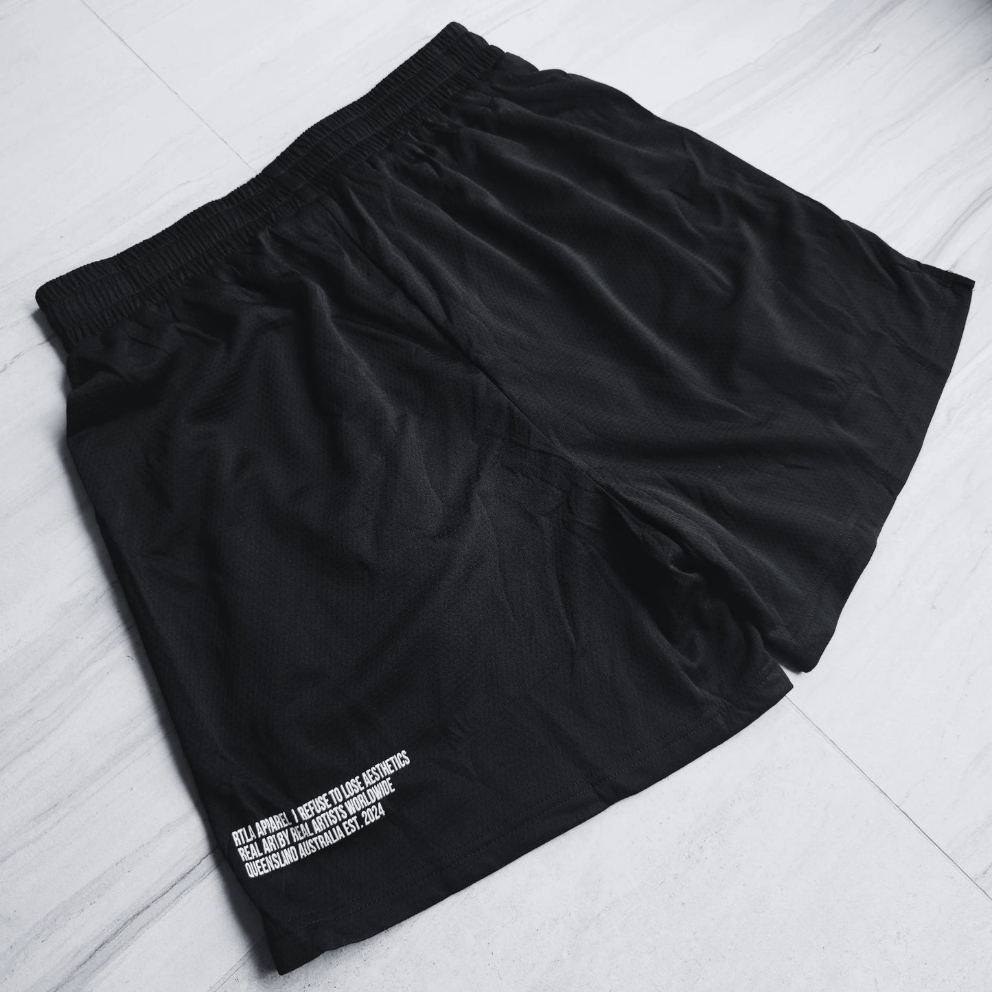 Black shorts with white text on a light gray surface