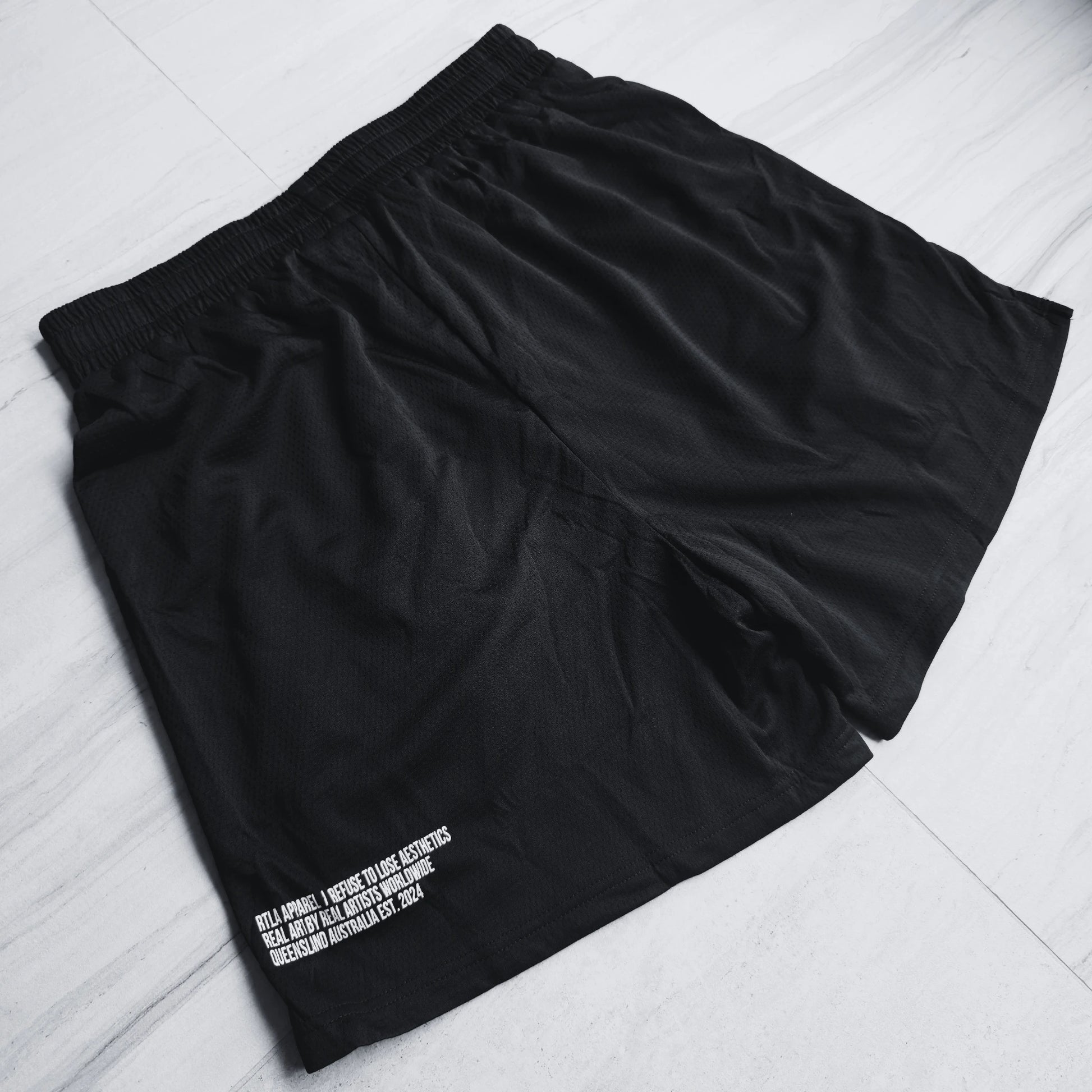 Black shorts with white text on a light gray surface
