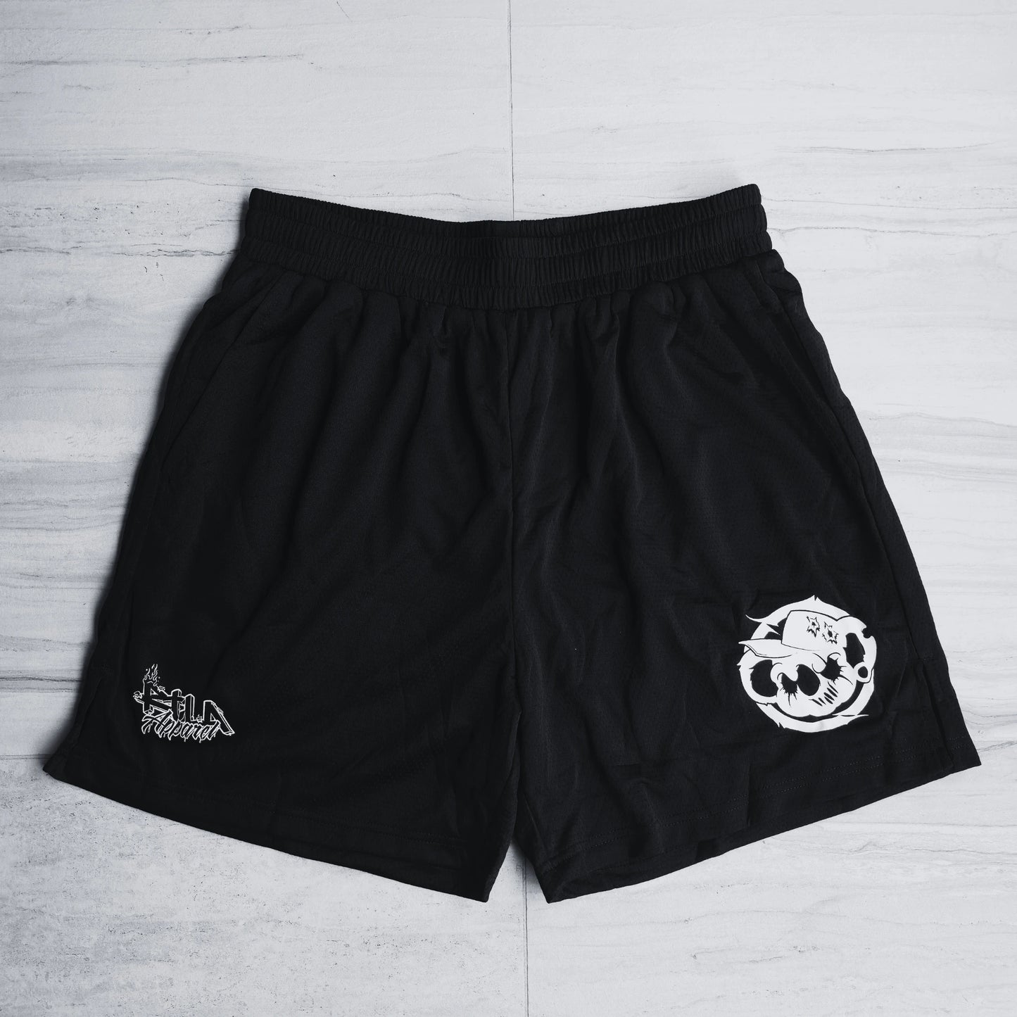 Black shorts with white logos on a light gray background