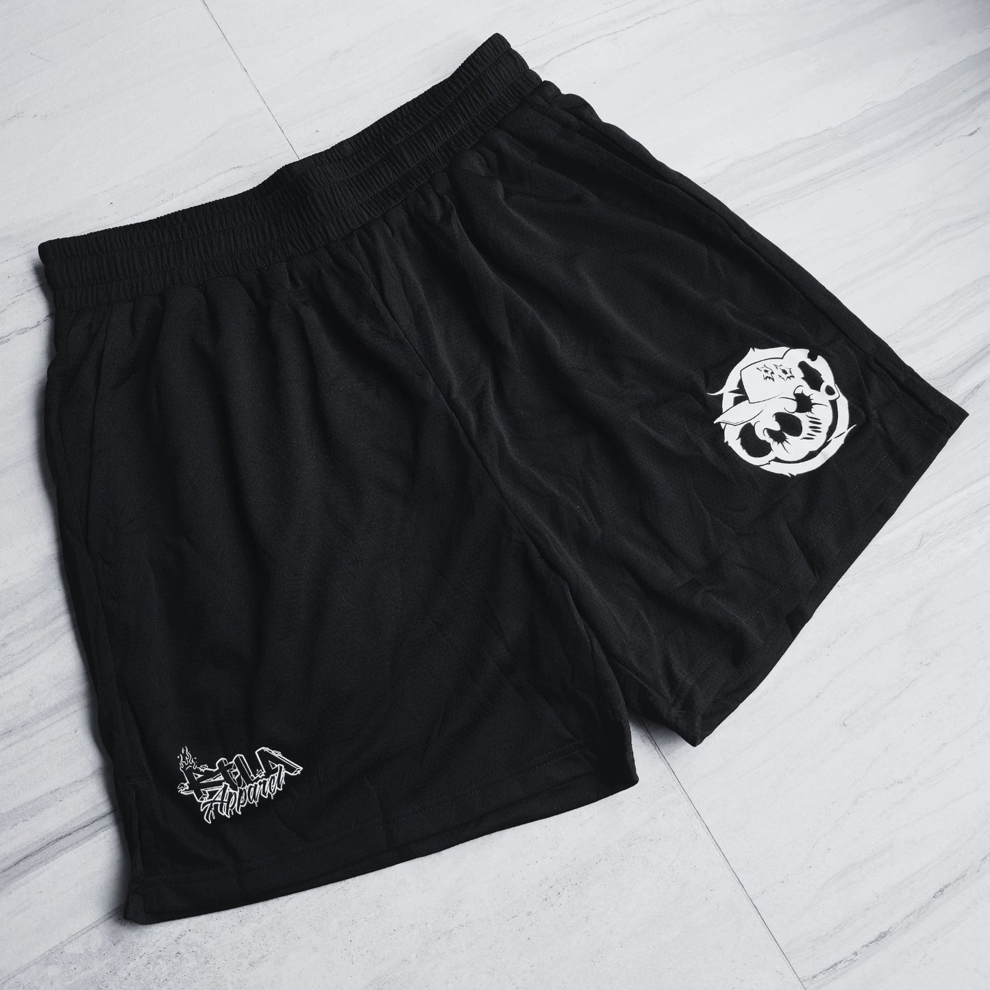 Black shorts with white logos on a light gray floor