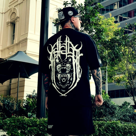 Man wearing a black t-shirt with a white graphic design outdoors.
