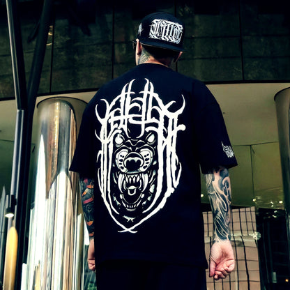 Person wearing a black t-shirt with white graphic design and a cap, standing in an urban setting.