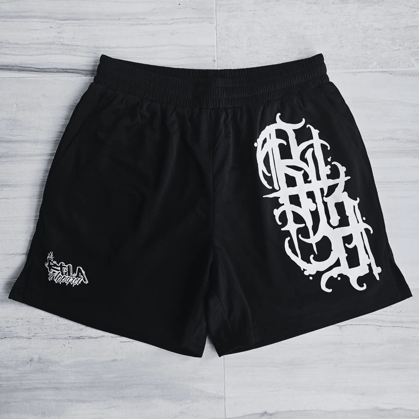 Black shorts with white graphic design on a light wooden floor
