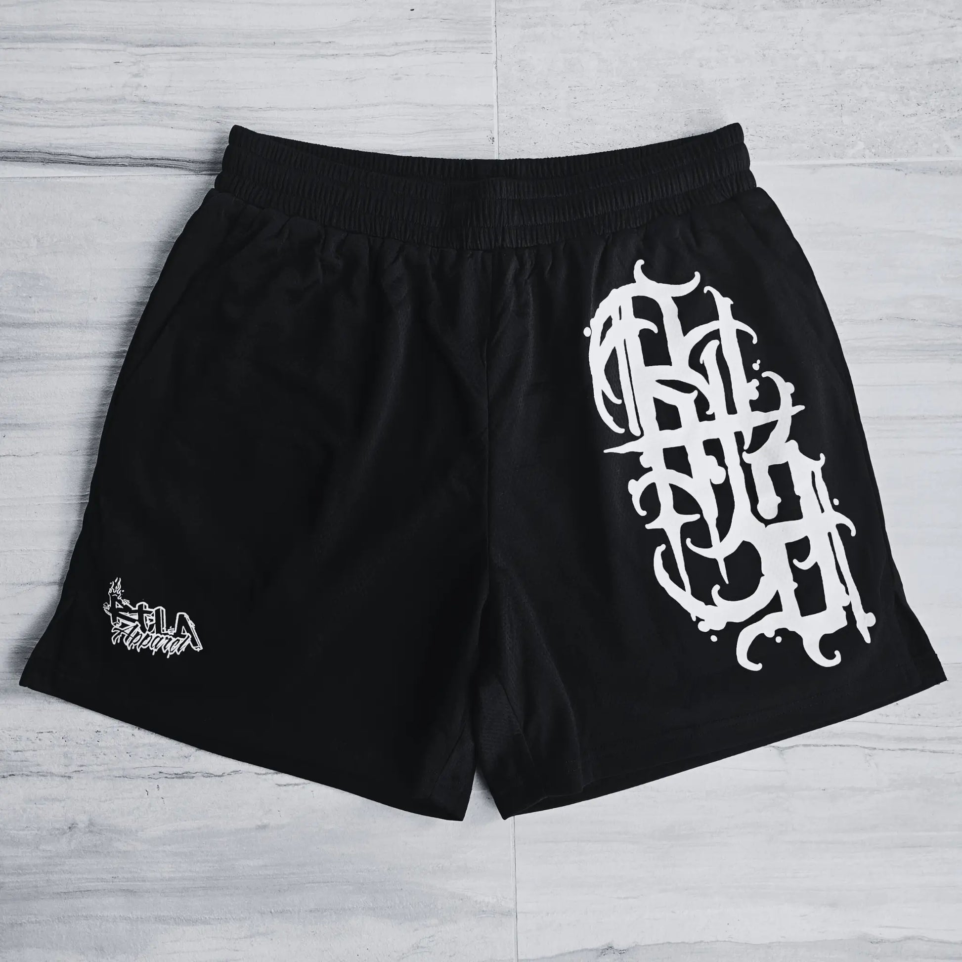 Black shorts with white graphic design on a light wooden floor
