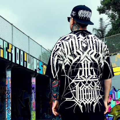 Person wearing a black and white patterned shirt with a cap, standing in front of a colorful mural.