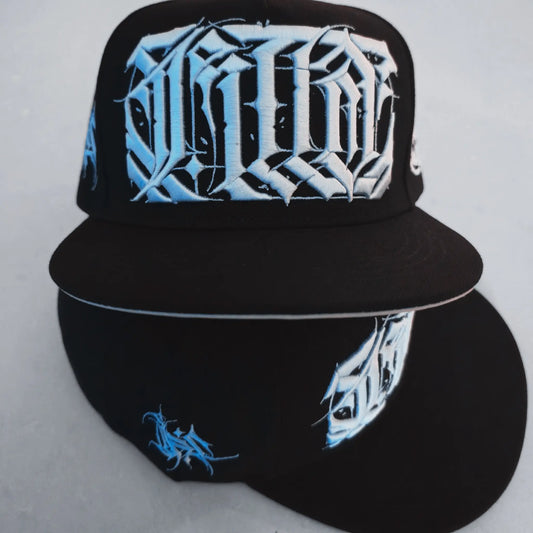 Black cap with white and blue designs on a light gray background