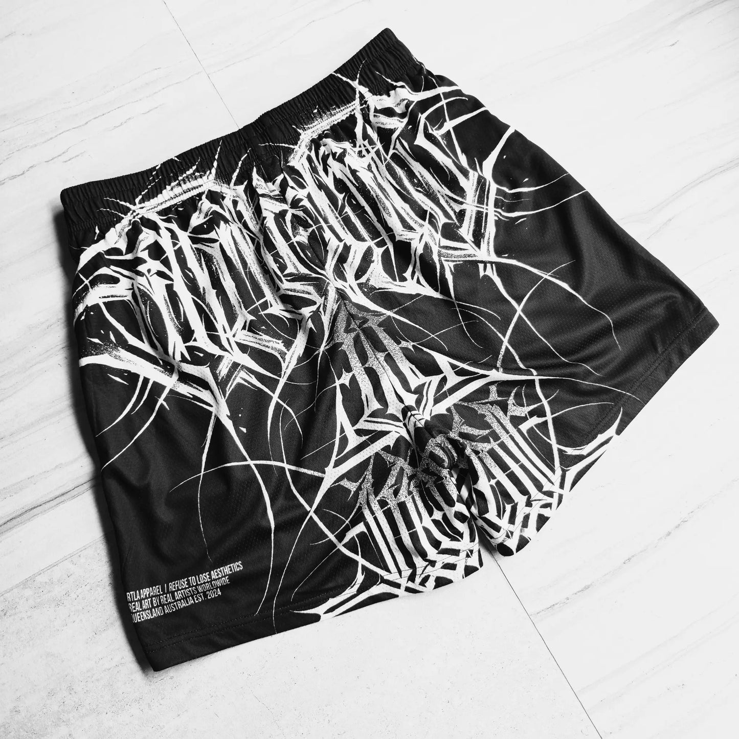 Black shorts with white abstract design on a light gray floor