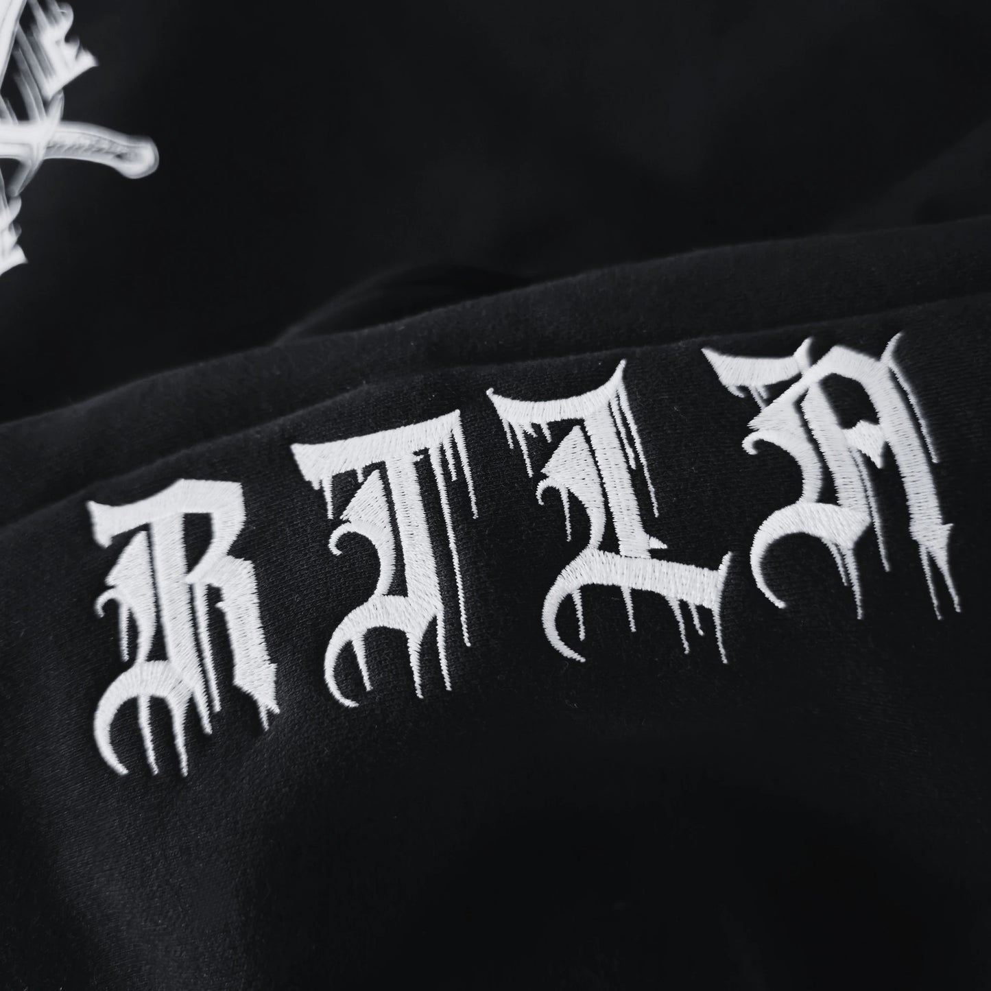 Black fabric with white 'RAT' text design on a dark background