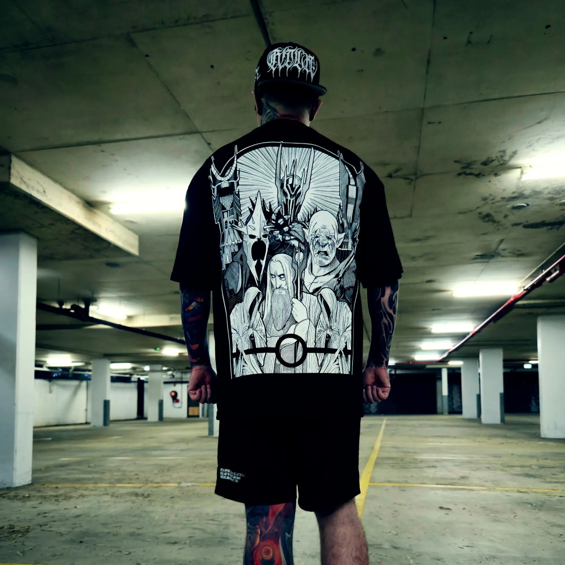 Person wearing a black t-shirt with graphic designs in an underground parking lot