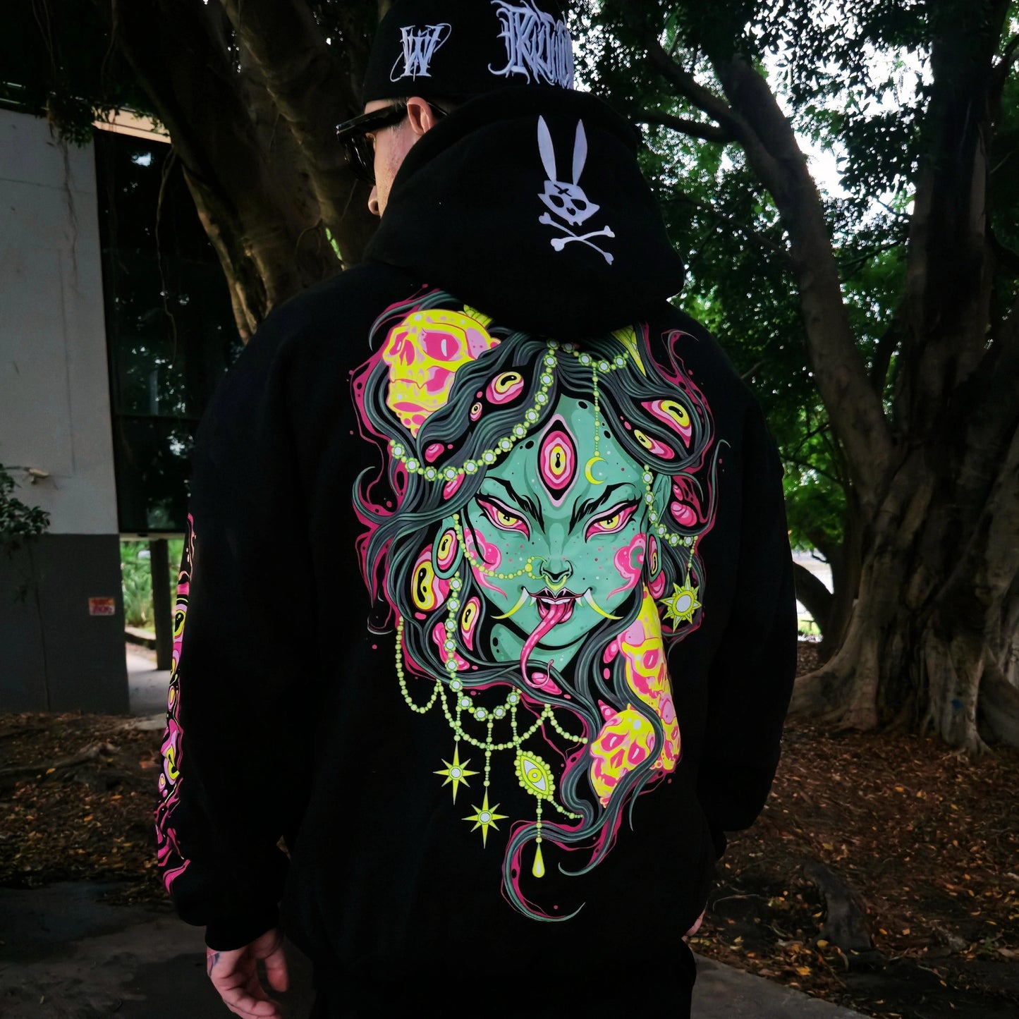 Person wearing a black hoodie with a colorful graphic design outdoors.