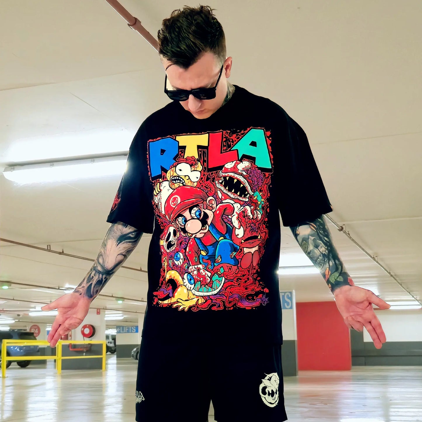 Person wearing a black t-shirt with colorful graphics and text in an indoor setting