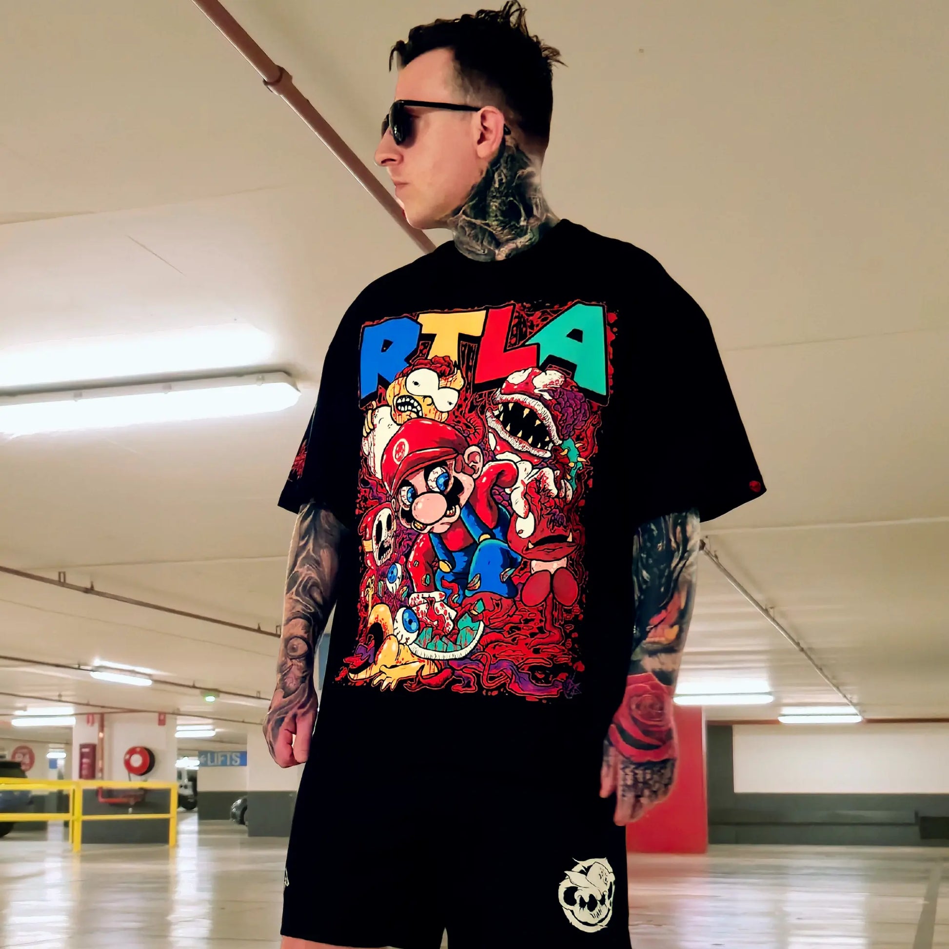 Person wearing a black t-shirt with colorful graphics and text in an indoor setting