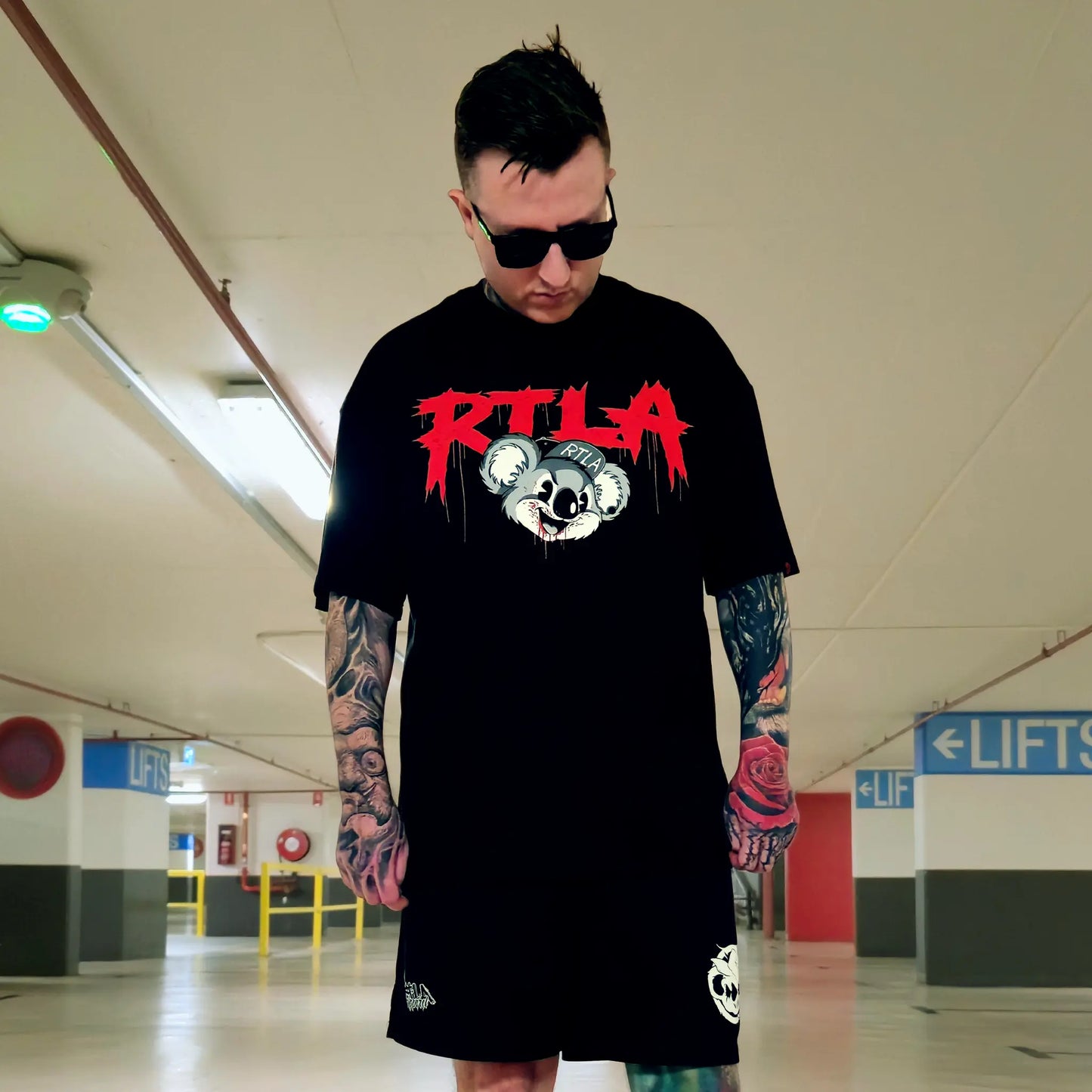 Person wearing a black t-shirt with a red and white graphic design in an indoor setting.