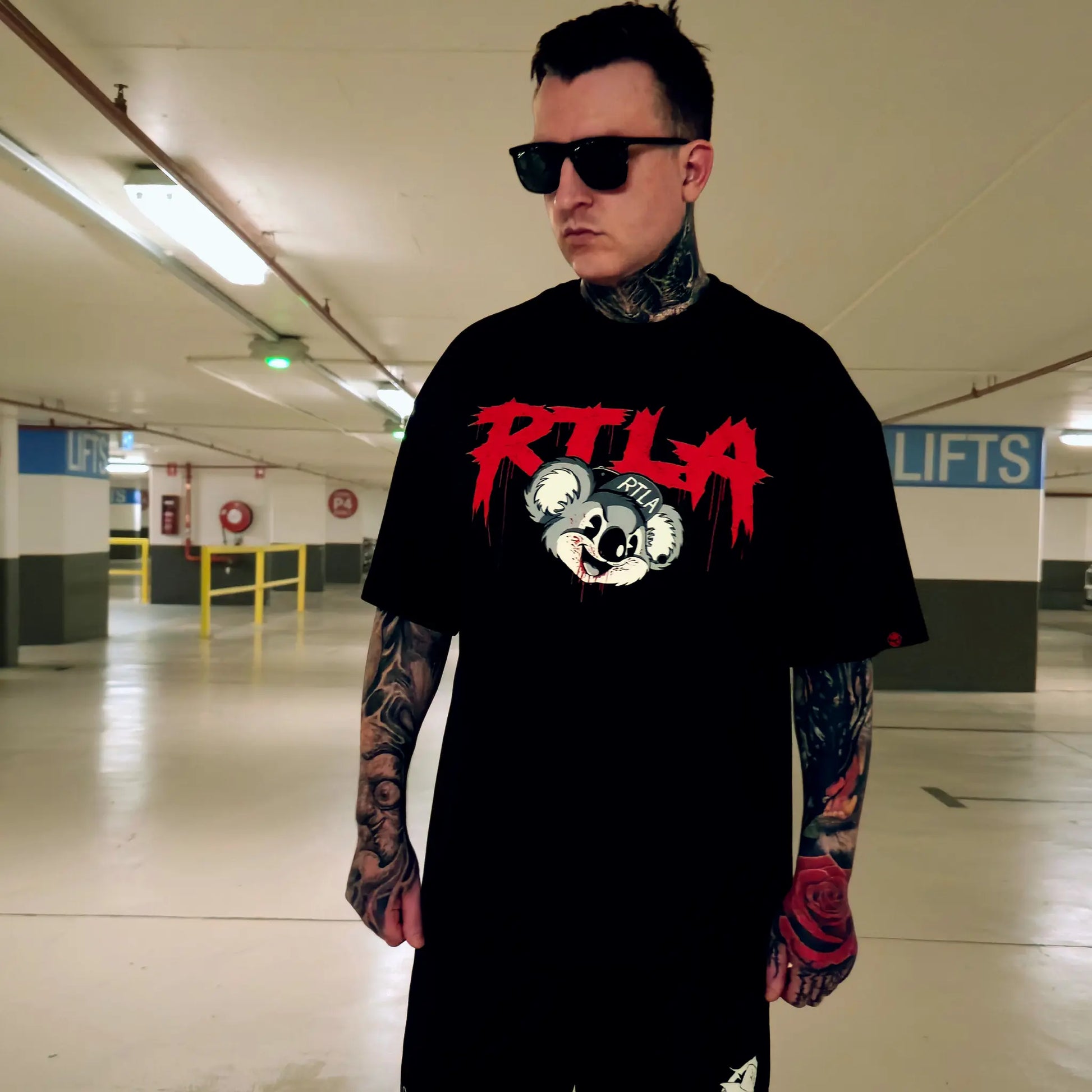 Man wearing a black t-shirt with red and white graphics in an indoor setting