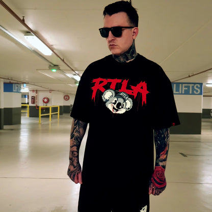 Man wearing a black t-shirt with red and white graphics in an indoor setting