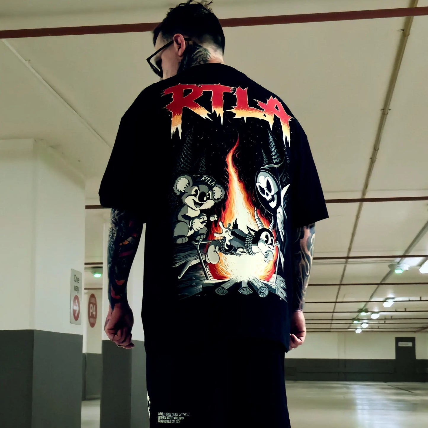 Person wearing a black t-shirt with colorful graphics and 'RTLA' branding in an indoor setting.
