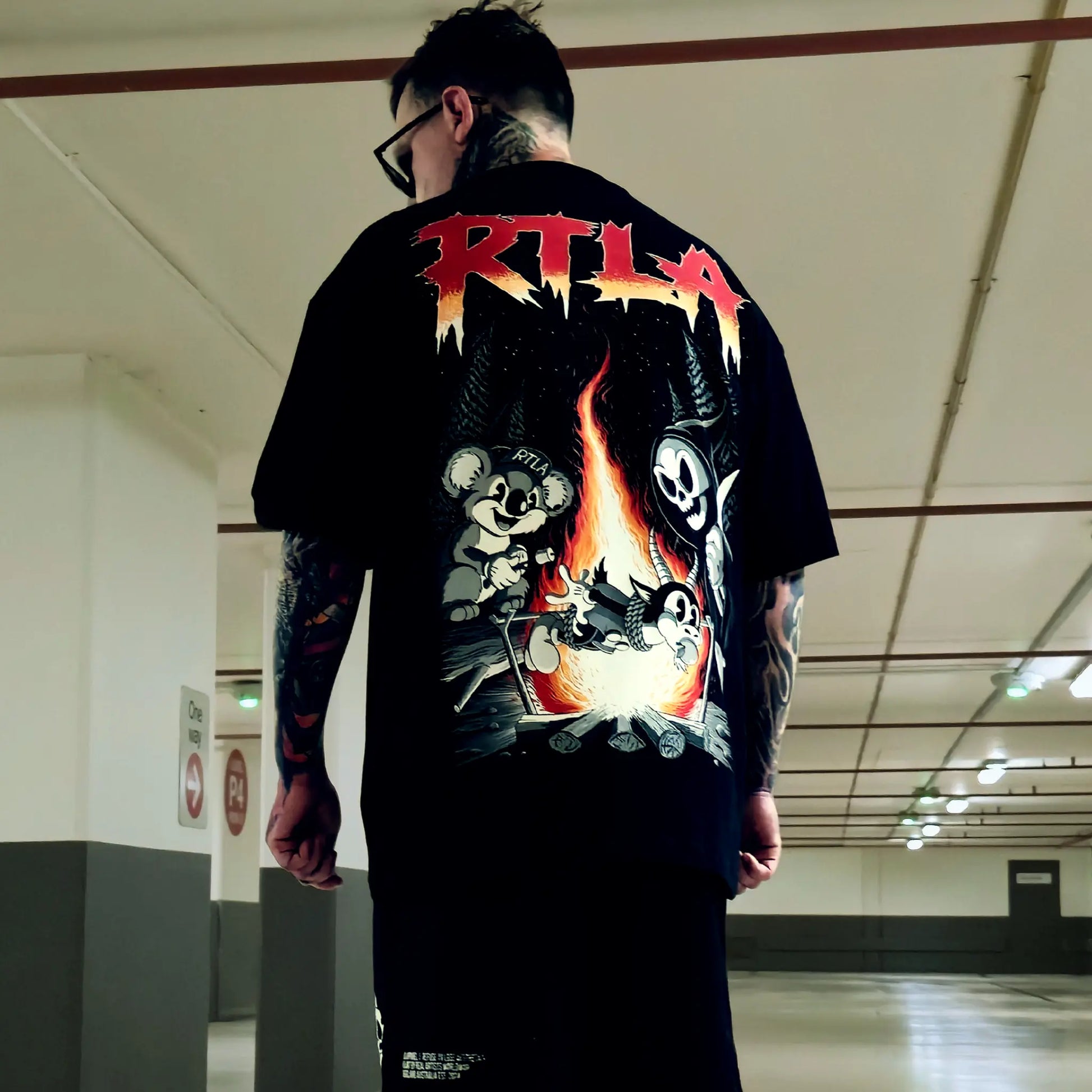 Person wearing a black t-shirt with colorful graphics and 'RTLA' branding in an indoor setting.