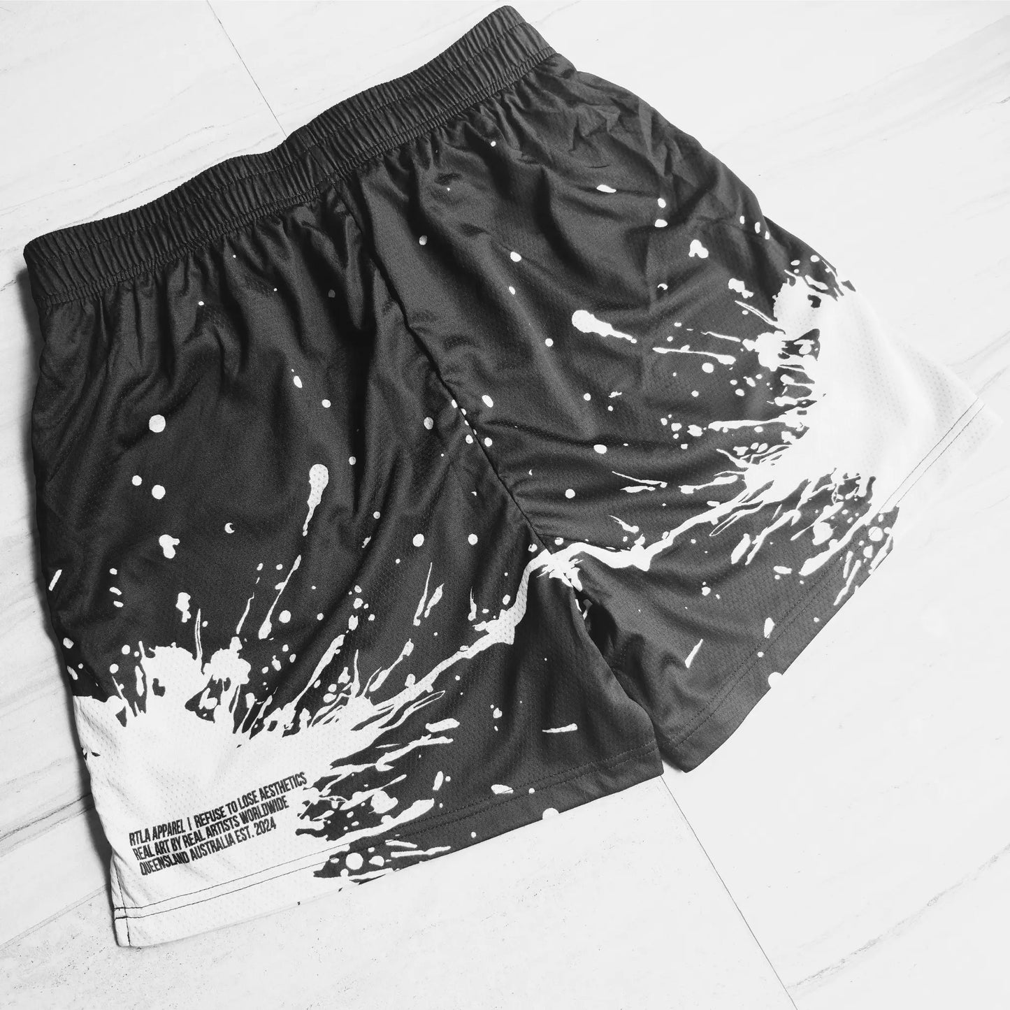Black shorts with white splatter design on a light gray background