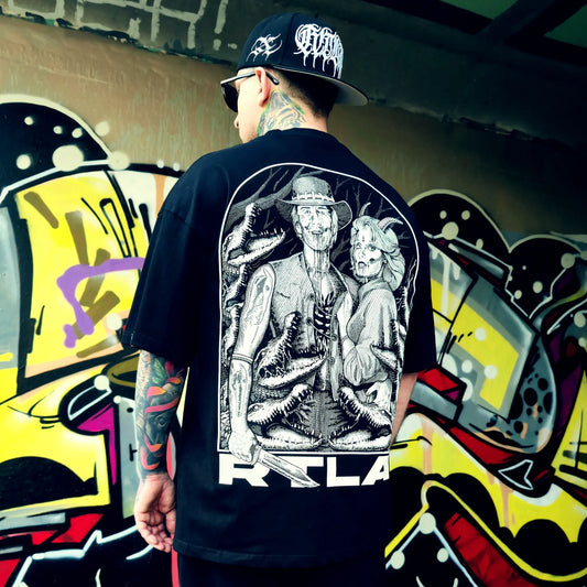 Person wearing a black t-shirt with a graphic design in front of a graffiti wall. RTLA-Apparel