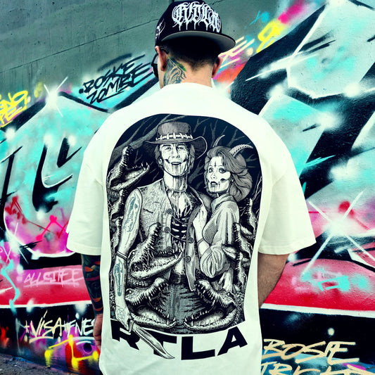 Person wearing a white t-shirt with a black and white graphic design, standing in front of a colourful graffiti wall. RTLA-Apparel