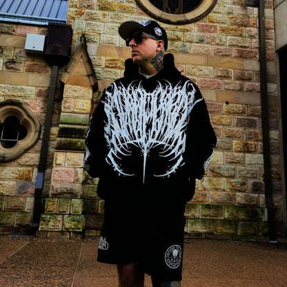 Person wearing a black hoodie with white skeleton design in front of a brick wall.