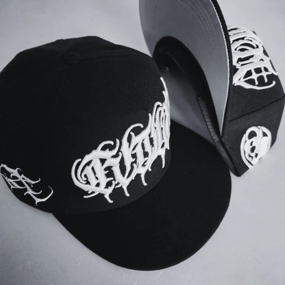 A black snapback cap with white 3D embroidered lettering and an artist signature logo on the side. RTLA-Apparel