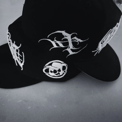 A black snapback cap with white 3D embroidered lettering and an artist signature logo on the side. RTLA-Apparel