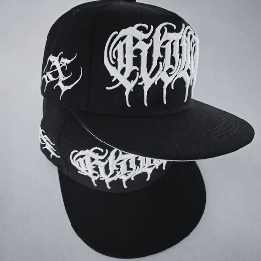 A black snapback cap with white 3D embroidered lettering and an artist signature logo on the side. RTLA-Apparel