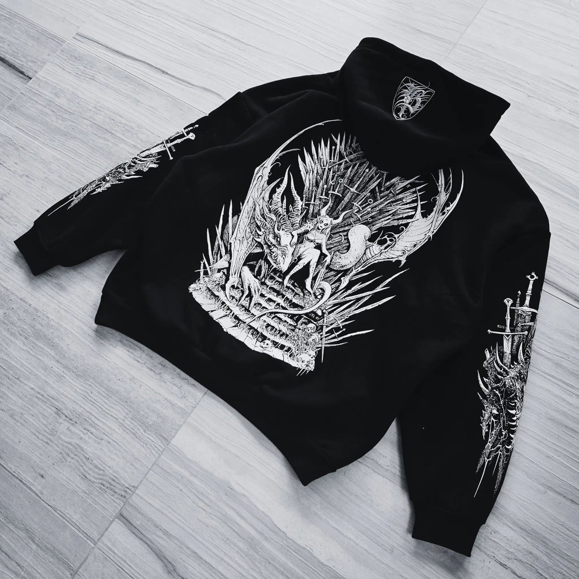 Black hoodie with intricate white designs on a wooden floor