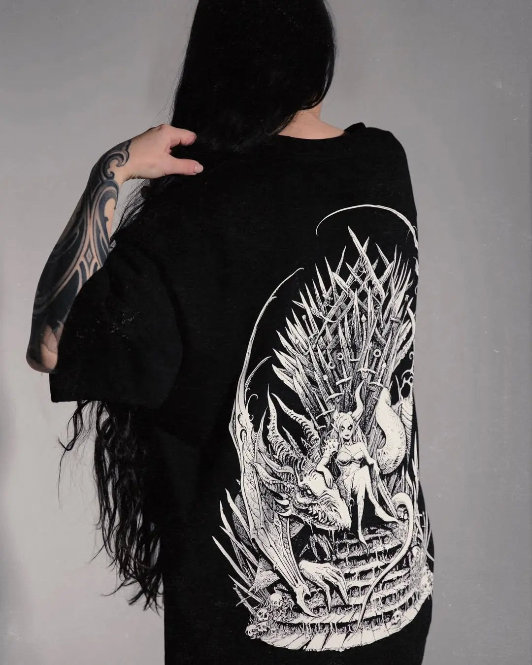 Person wearing a black shirt with a detailed white design on the back, featuring a dragon and a castle.