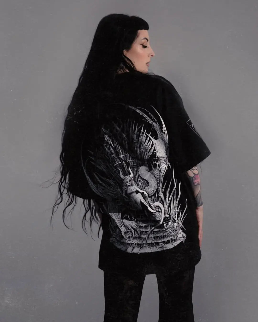 Person wearing a black t-shirt with a detailed design on the back against a gray background