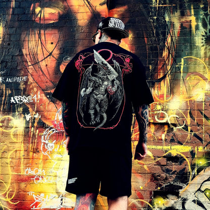 Person wearing a black t-shirt with a graphic design, standing in front of a colorful graffiti wall.