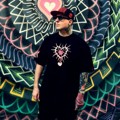 Person wearing a black t-shirt with a unique design in front of a colorful mural.
