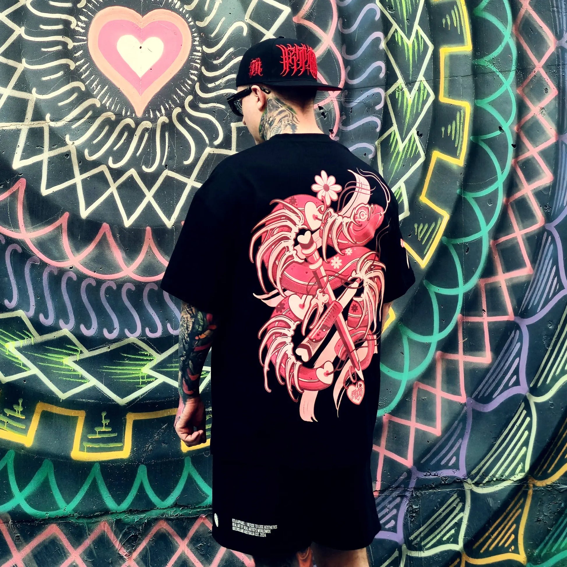 Person wearing a black t-shirt with a red dragon design, standing in front of a colorful wall.