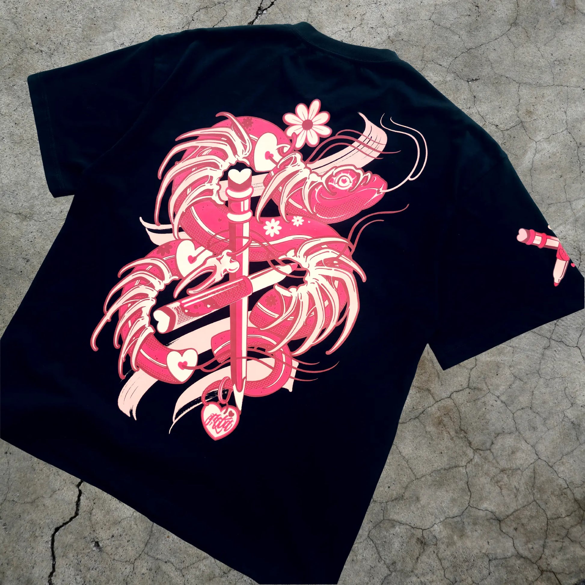 Black t-shirt with pink graphic design on a textured surface