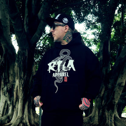 Person wearing a black hoodie with 'RVA Apparel' logo in a forest setting
