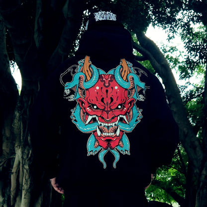 Person wearing a black hoodie with a red and blue dragon design in a forest setting