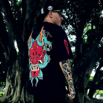 Person wearing a black t-shirt with a colorful dragon design outdoors.