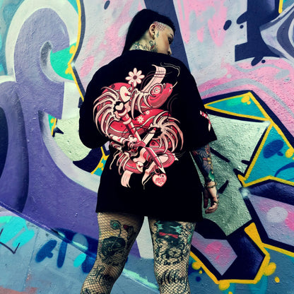 Person wearing a black hoodie with a red and pink floral design against a colorful graffiti wall.
